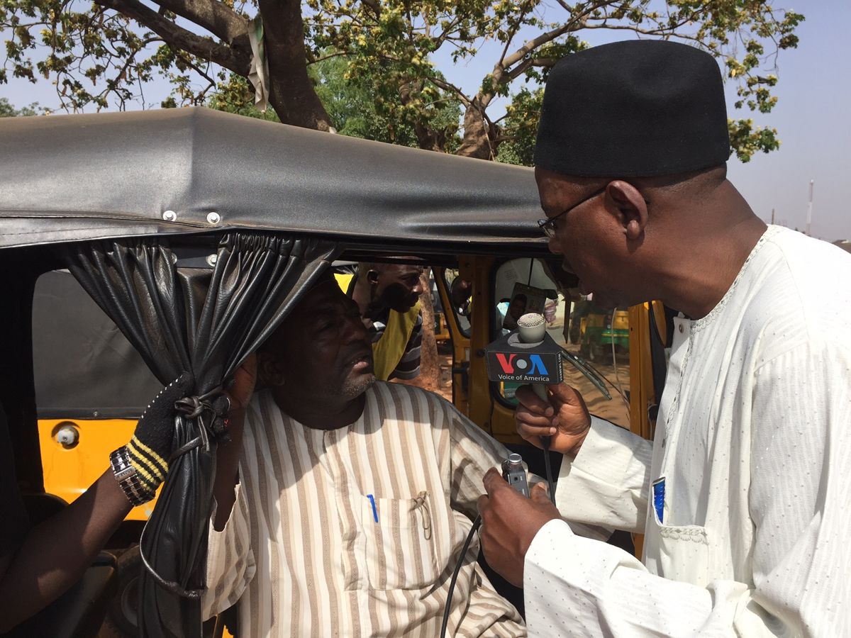A radio reporter interviewing residents in Kaduna