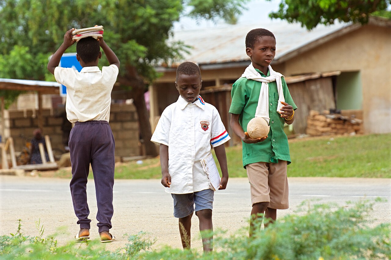Three pupils in school uniform walking to school along the roadside in the morning