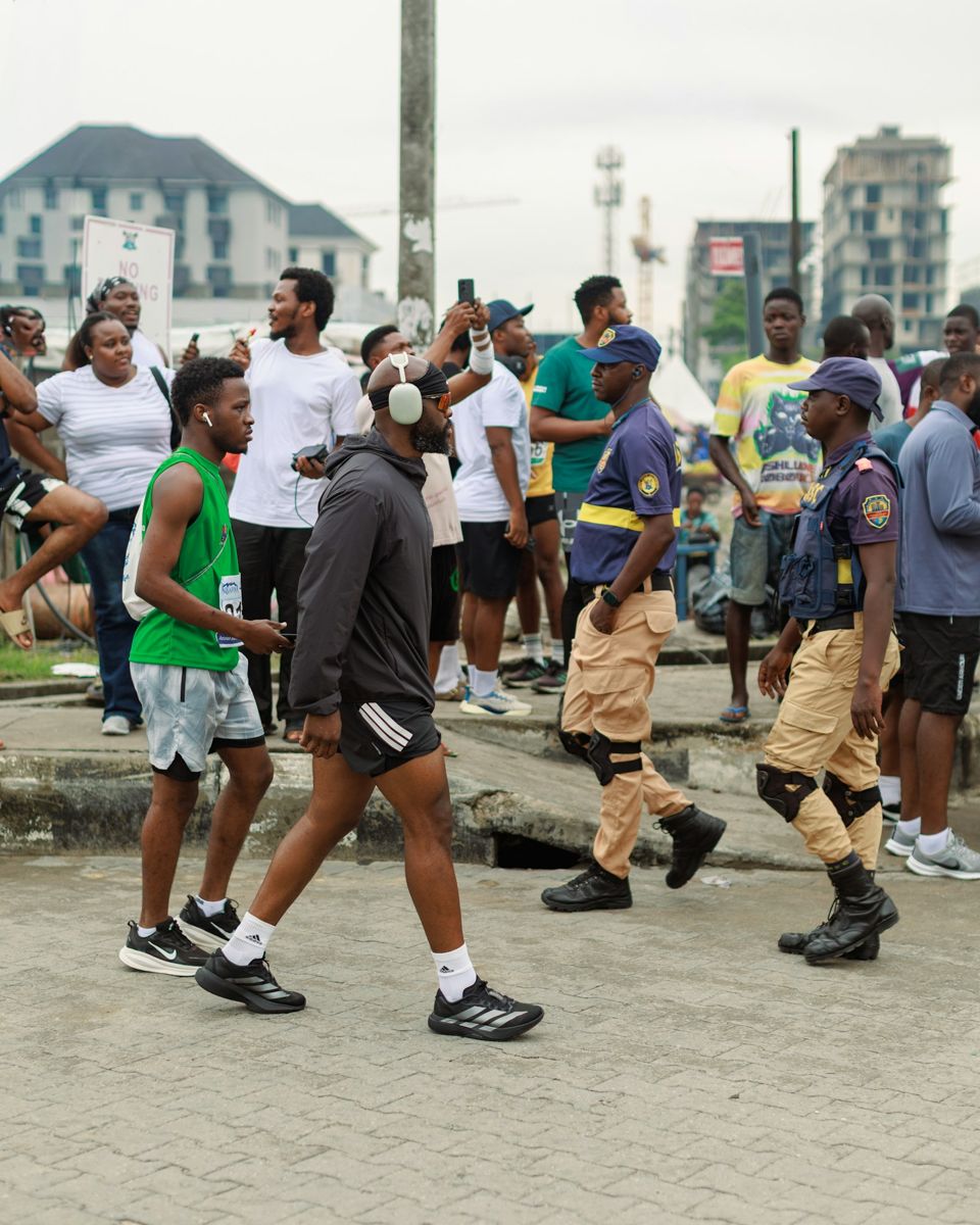 Uniformed security personnel walking with a crowd at an outdoor event in Nigeria
